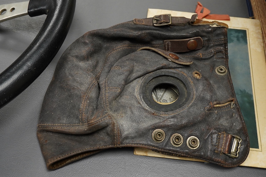 Racing ephemera, including; a Moto-lite steering wheel, a driver's leather cap, an enamelled Le Mans pilot’s radiator badge, signed photograph of Prince Michael Kent standing next to a 12 cylinder single seat racing car